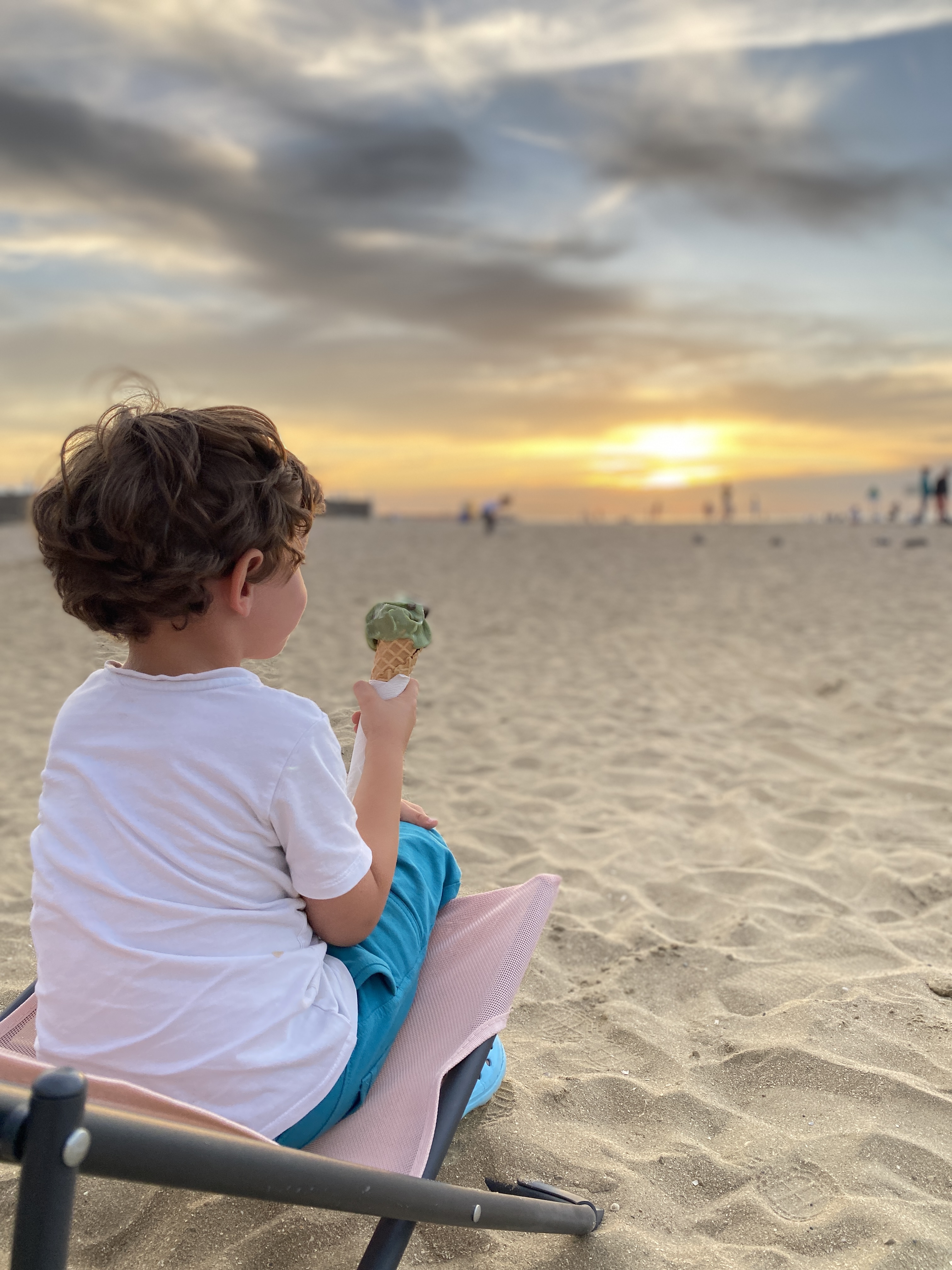Enfant avec une glace face au coucher de soleil sur la plage